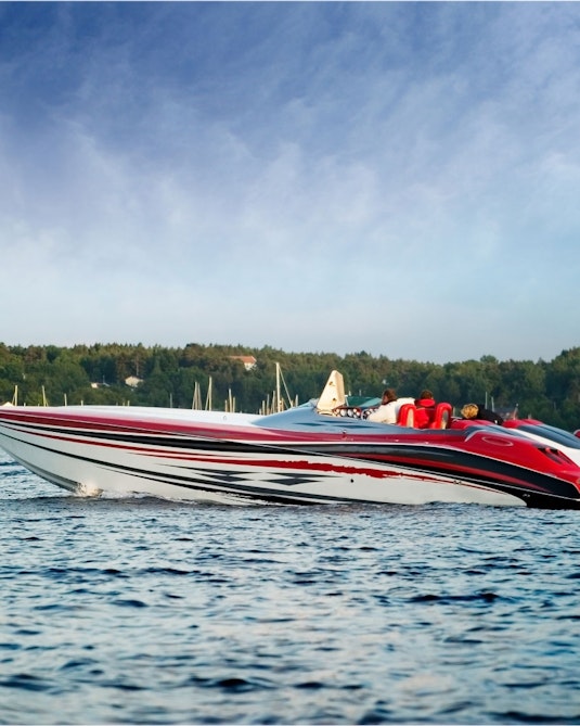 A high-performance speedboat floating in front of a harbor on a sunny afternoon.
