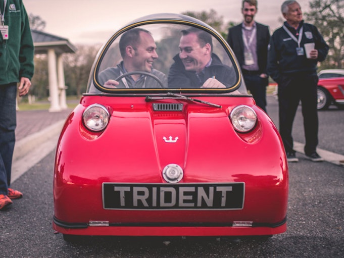 Two men smiling in a red Maserati Trident