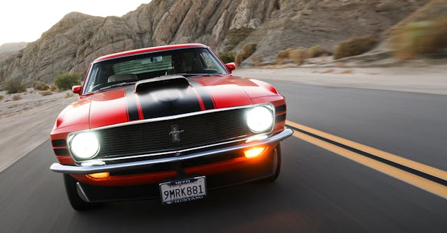 red classic mustang driving through the mountains
