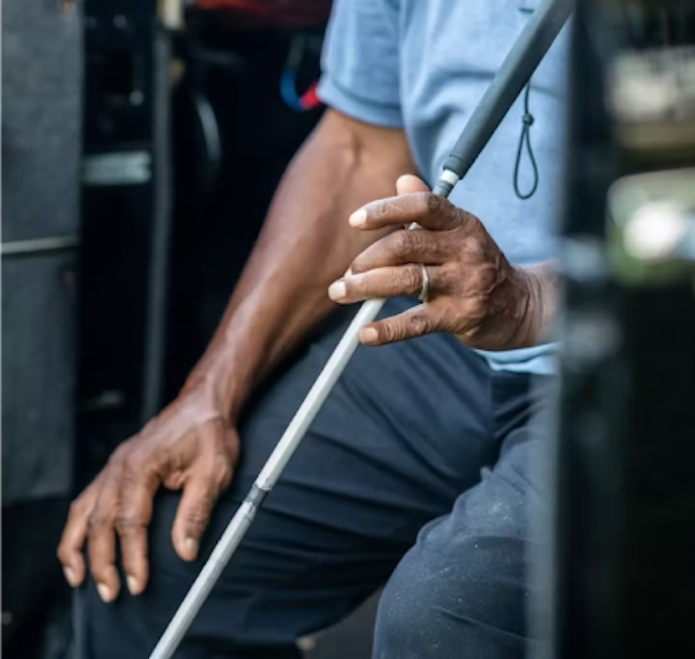Close up photo of a man's hands holding a white cane