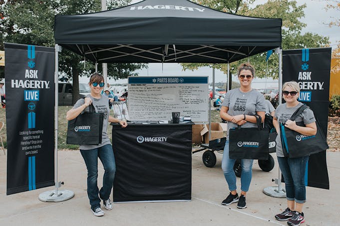 3 people standing at a Hagerty event holding Hagerty marketing materials.