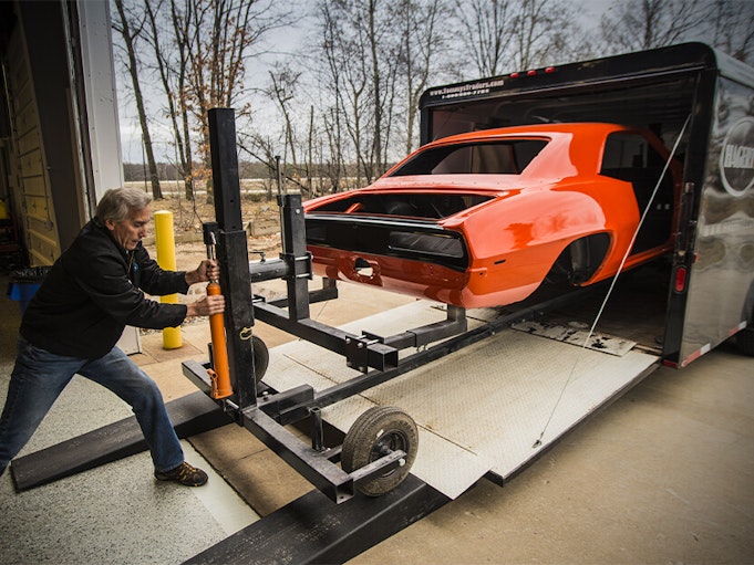 An orangish red collector vehicle being pulled from a trailer.