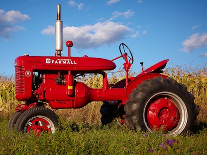 A red collector tractor parked in a field with blue sky in the background.