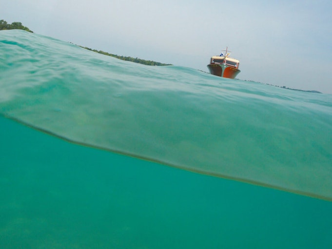 A wooden boat floating on top of a clear, turquoise body of water.