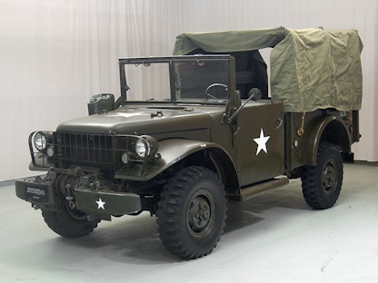 A collector military truck with a canvas cover, parked indoors.