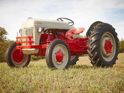 A cream and red collector tractor parked on a grassy lawn.