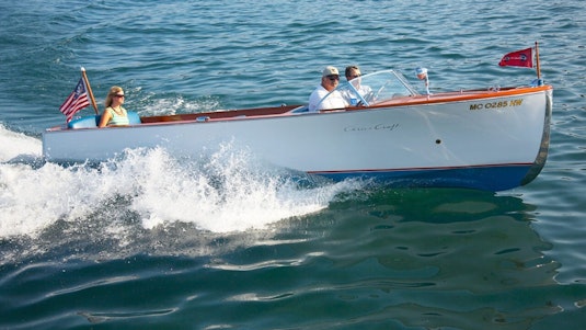 A family of three speeding through water in a collector white boat.