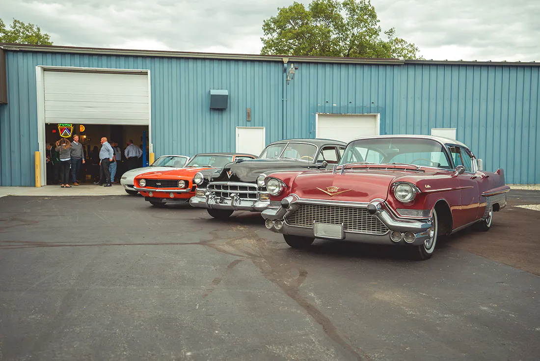 Four vintage collector vehicles parked side by side in front of the Hagerty Learning Garage.