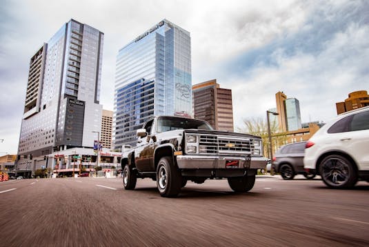 Collector truck traveling on road with traffic in city.