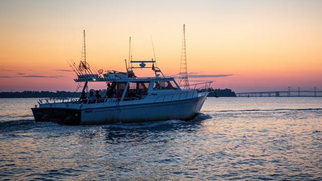 A boat motors at sunset near the Mackinac Bridge