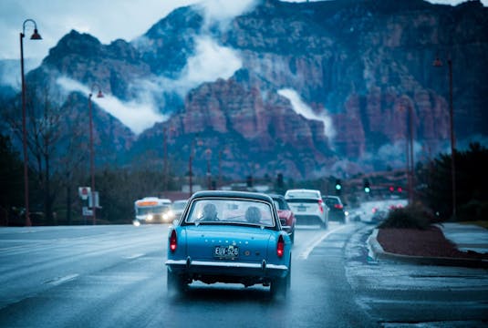 Blue collector vehicle driving in mountain region on wet roads.
