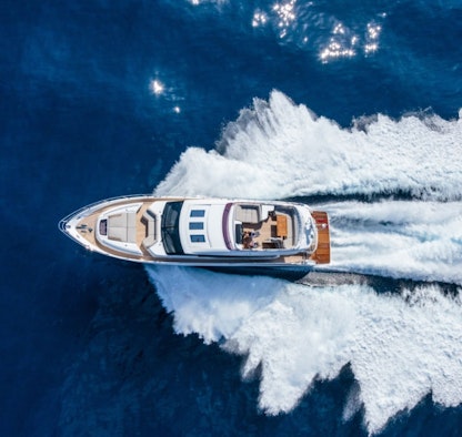 A white yacht pictured from above being directed through water.