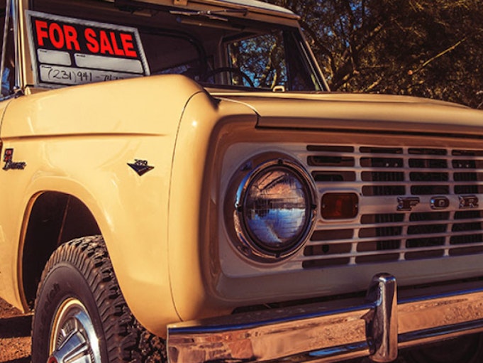 Yellow classic Ford Bronco with a For Sale sign in the window.
