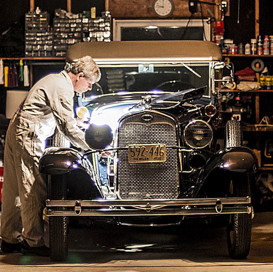 A man working on a collector vehicle in a garage.