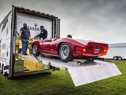A red collector convertible being transported from a trailer.