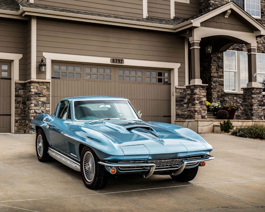 blue corvette parked in driveway of house