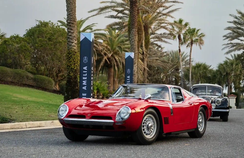 A red classic sportscar with palm trees in the background