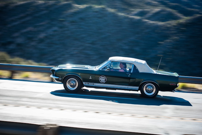 A green Shelby Cobra GT 500 driving along the mountainside.