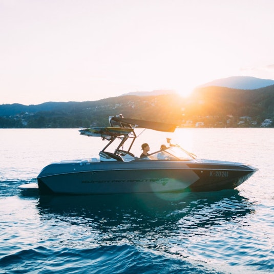 A wakeboard boat cruising at sunset