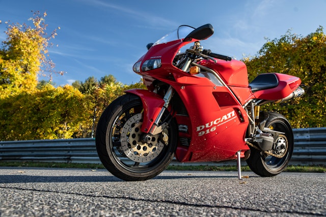 A red Ducati parked on the side of the road on a sunny day