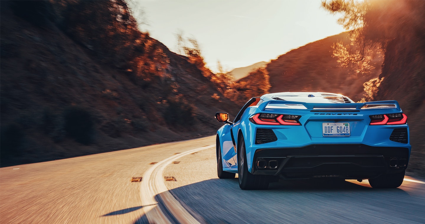 A blue Corvette being driven down a curvy road.